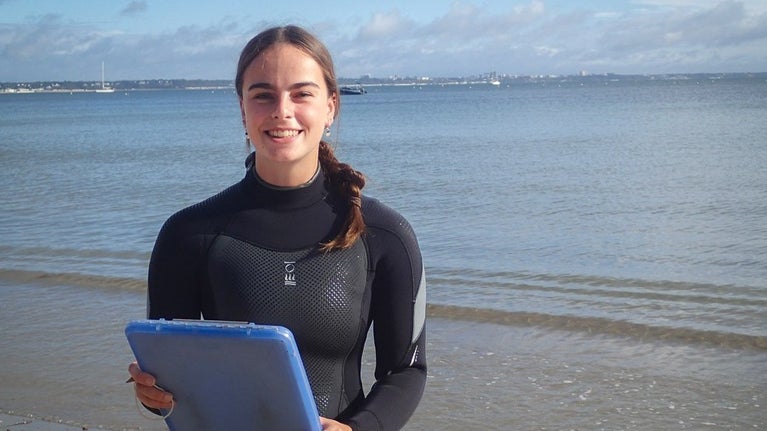 Woman holding clipboard with sea behind